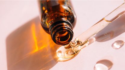 A close up of a bottle releasing a serum