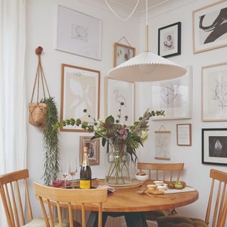 A dining room with a gallery wall and a dining table with a vase of flowers