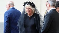 Queen Camilla smiles, wearing a black dress and veil, in Vatican City on October 23, 2025