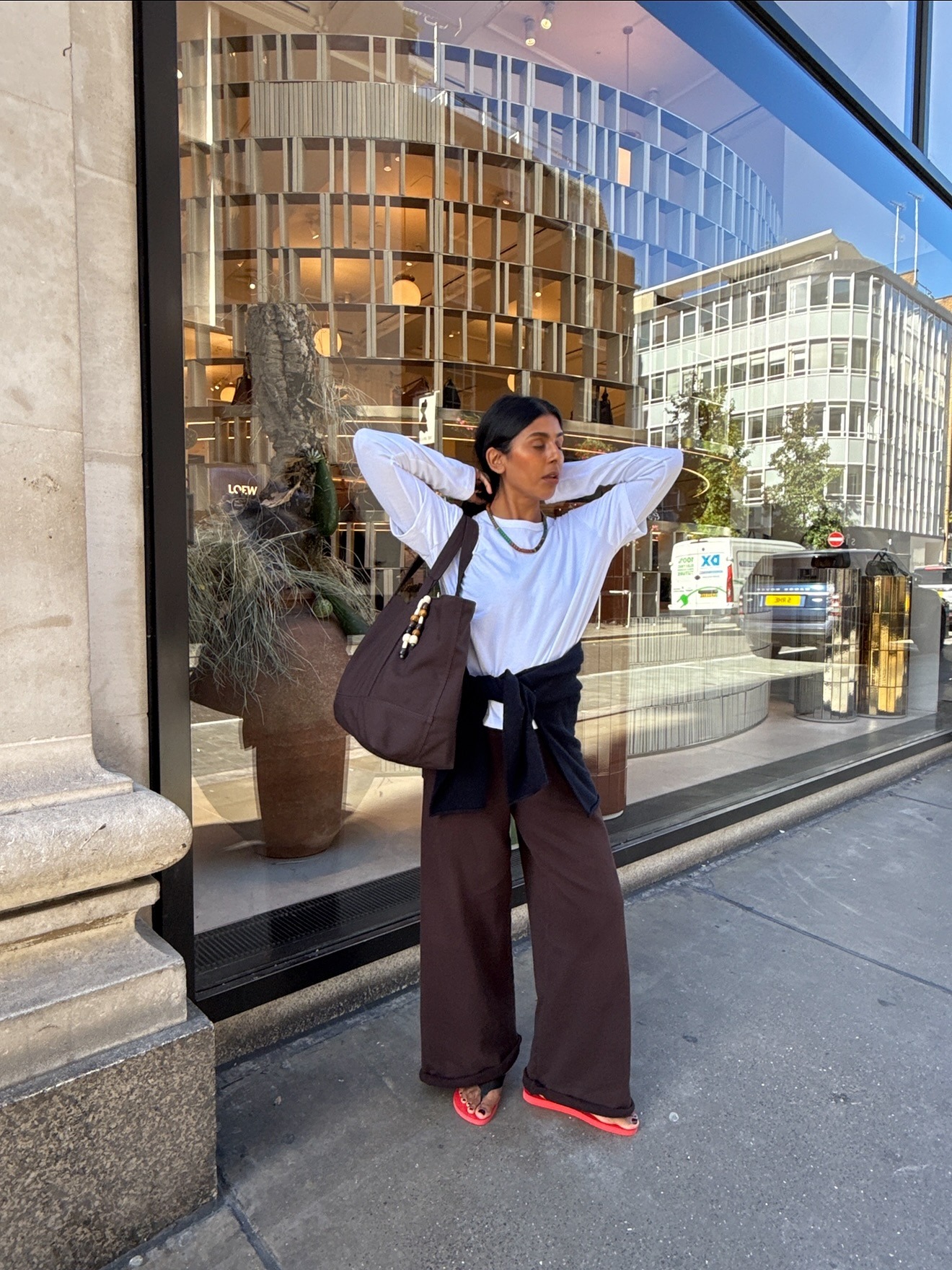 A woman in London wearing brown trousers and flip flops with a black pedicure