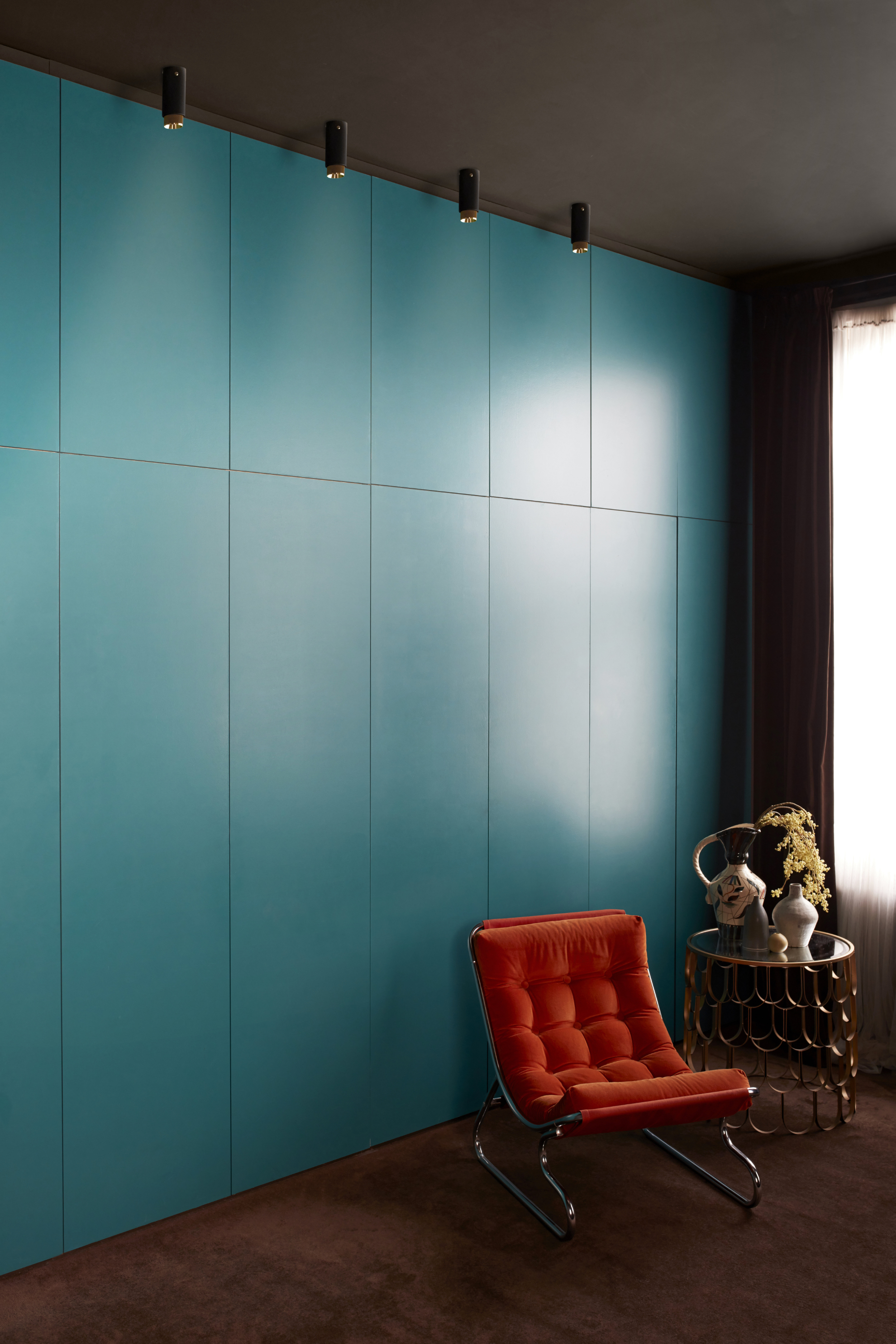 A tall teal coloured fitted wardrobe with spotlights hung above it
