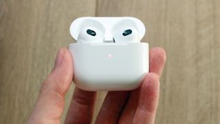 En hånd som holder Apple AirPods 3 i ladeetuiet.