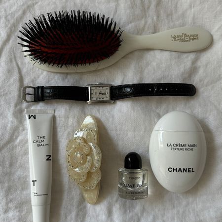 Spread of various beauty items, Mason Pearson hairbrush, Chanel handcream, watch, and Selor hair barette.