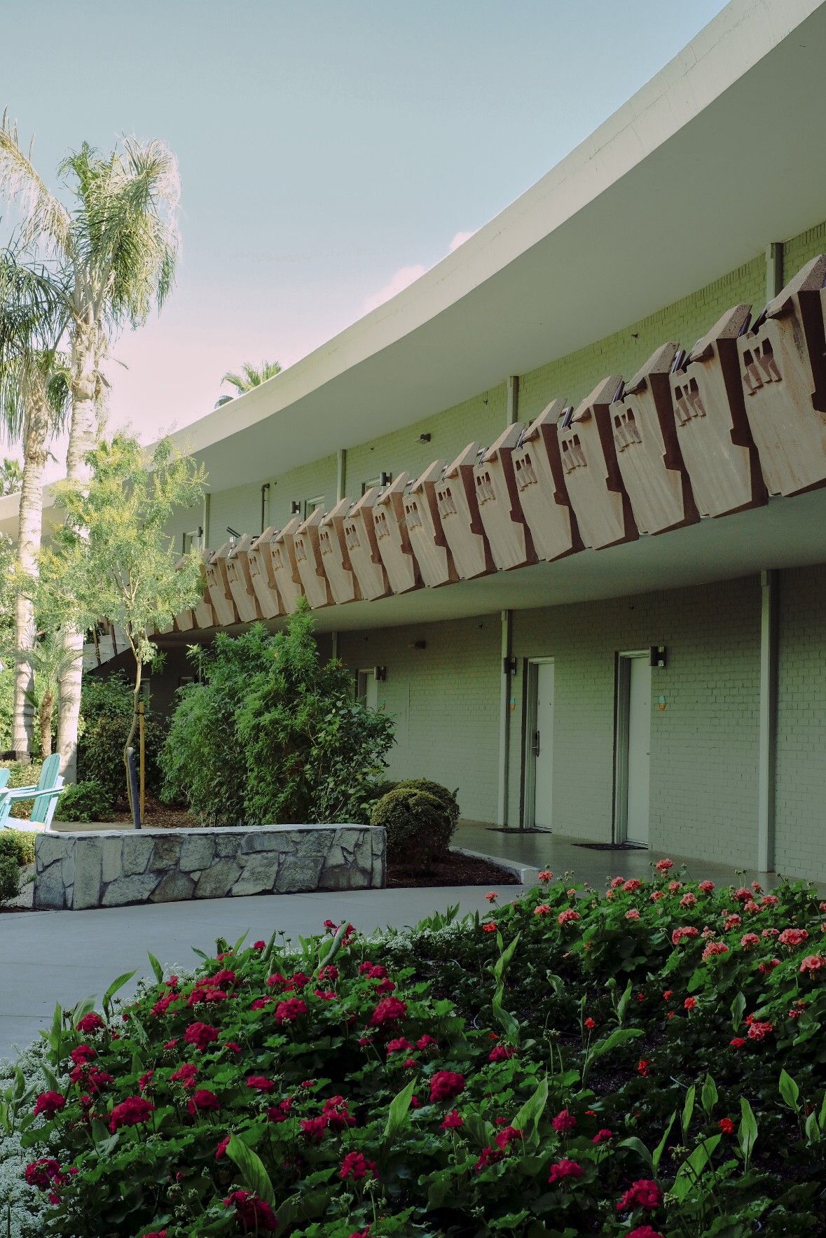 A series of photos showcasing a mid-century modern hotel with linear architecture, palm trees-filled exterior, and beautiful mountain views.