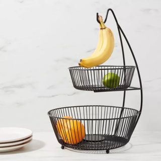 A two-tier fruit bowl with a hook for holding bananas