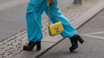 Sonia Lyson is seen wearing Louis Vuitton twist yellow leather bag, Louis Vuitton black and white top, Pull & Bear parachute blue pants, Saint Laurent shades and Louis Vuitton black leather monogram boots on August 24, 2022 in Berlin, Germany. 