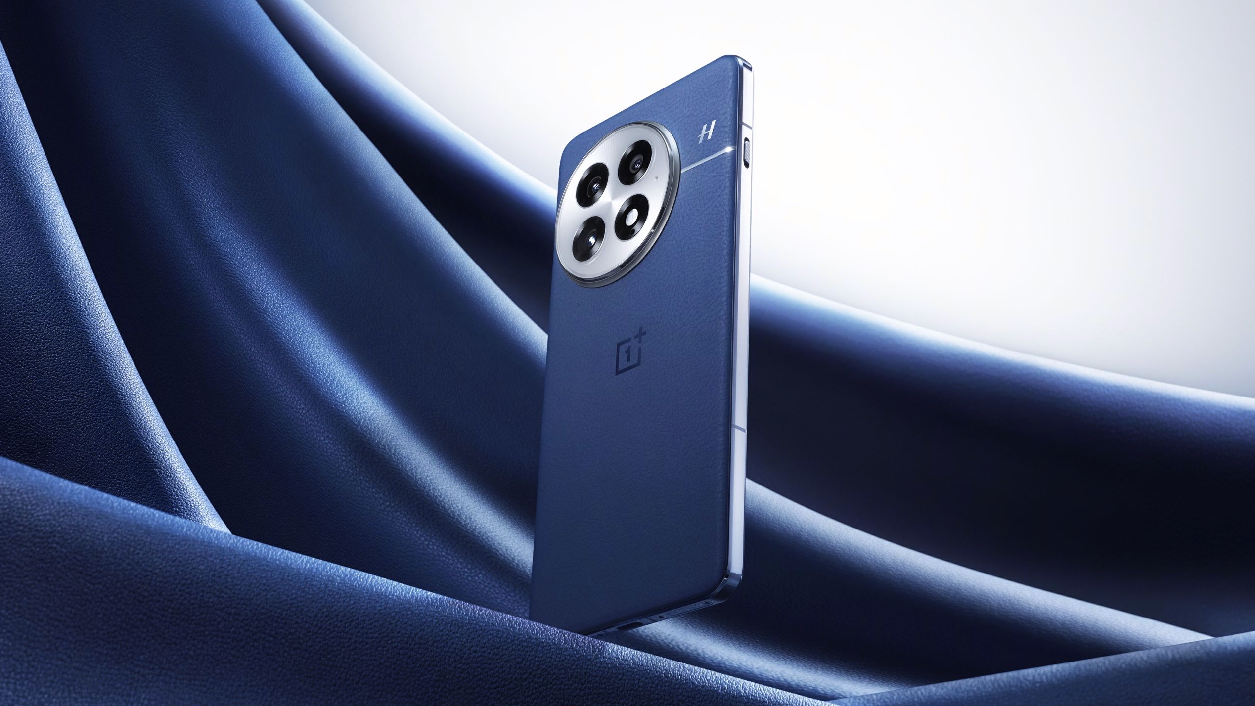 Téléphone OnePlus 13 bleu flottant au-dessus d'un tissu de velours bleu