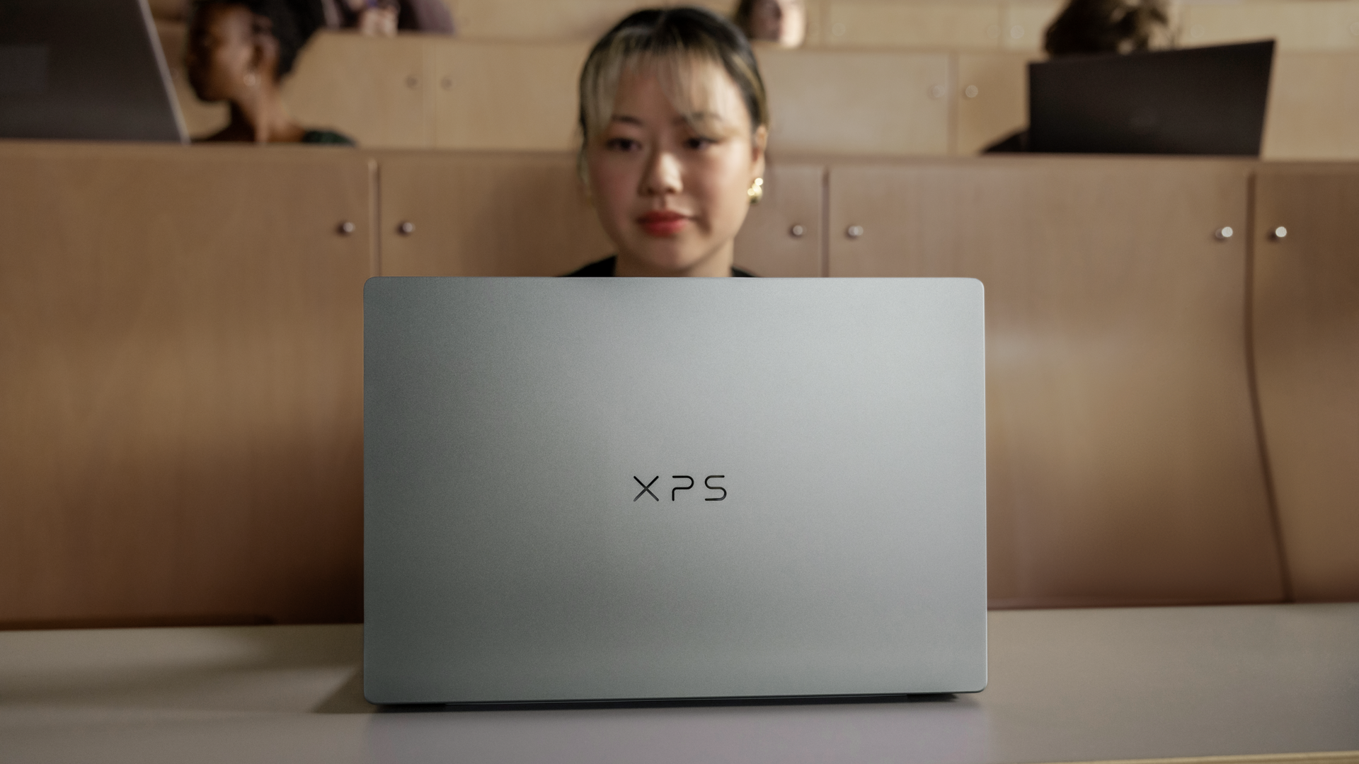 Dell XPS 13 on a desk, you can see the lid, and the owner's face above it