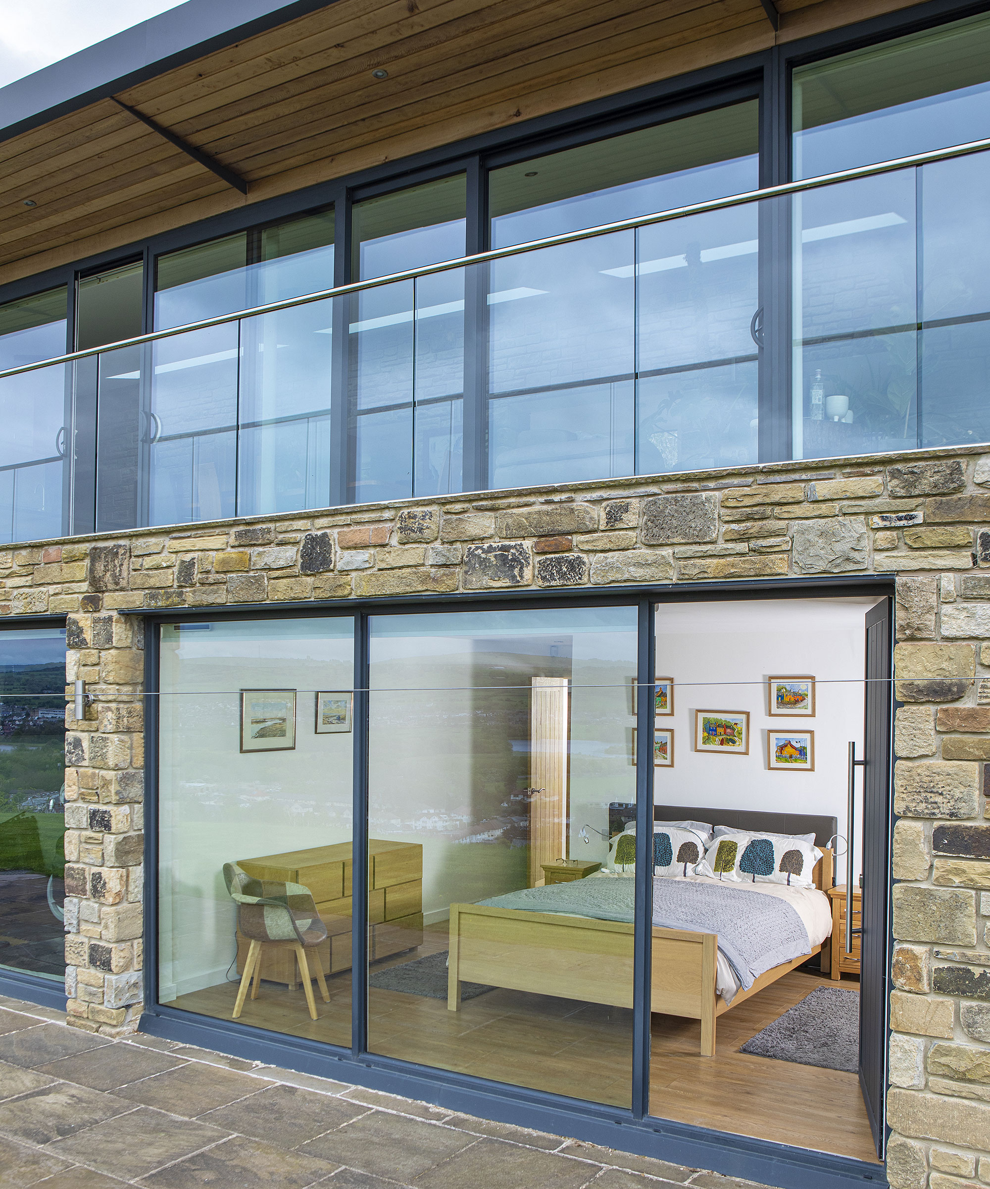 self-build home with stone exterior and sliding doors, with view into a ground floor bedroom