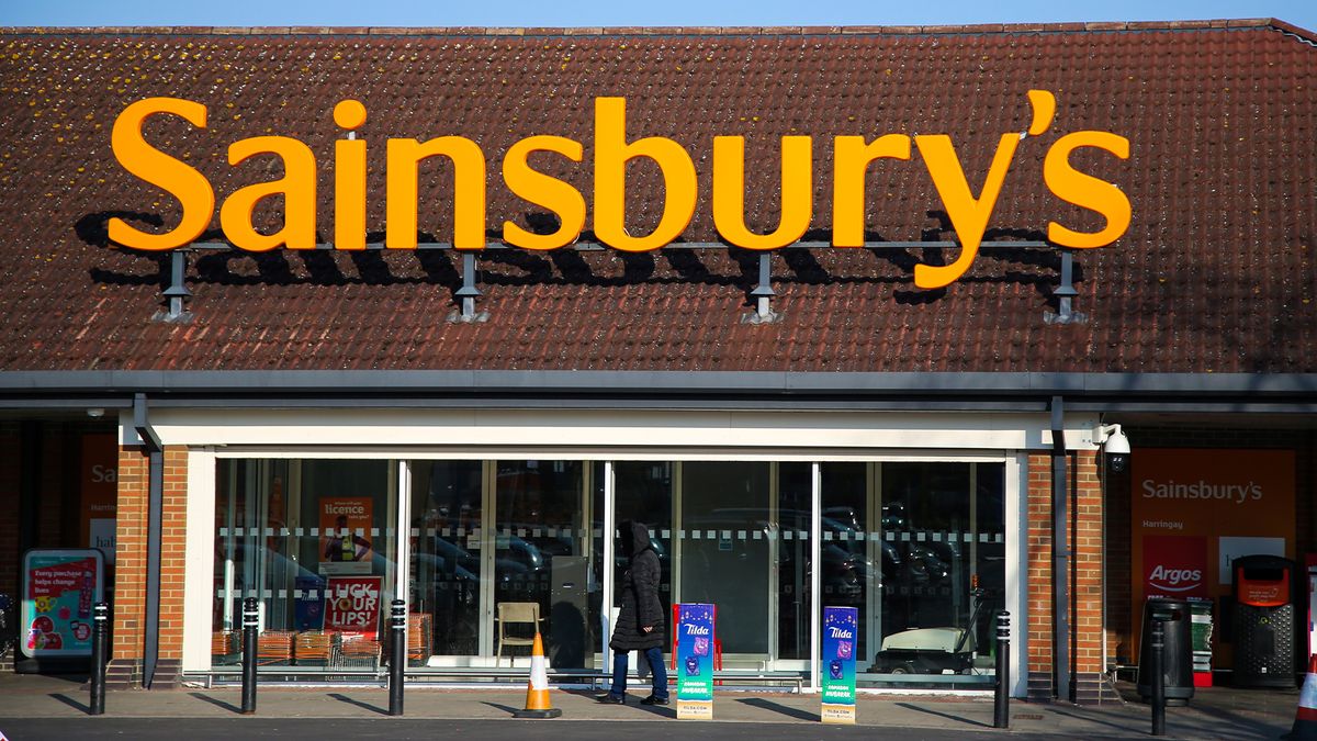 A woman walks past a branch of Sainsbury&#039;s supermarket.