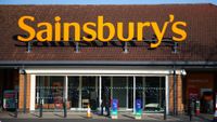 A woman walks past a branch of Sainsbury's supermarket.