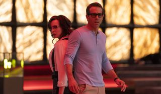 Free Guy Jodie Comer and Ryan Reynolds stand stunned, back to back