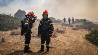 Firefighters photographed against a background of smokey skies in Rhodes