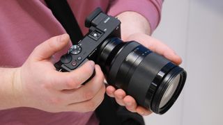 Sony FE 24-240mm lens attached to a Sony camera held in a pair of hands