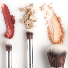 Three makeup brushes with product spread above 