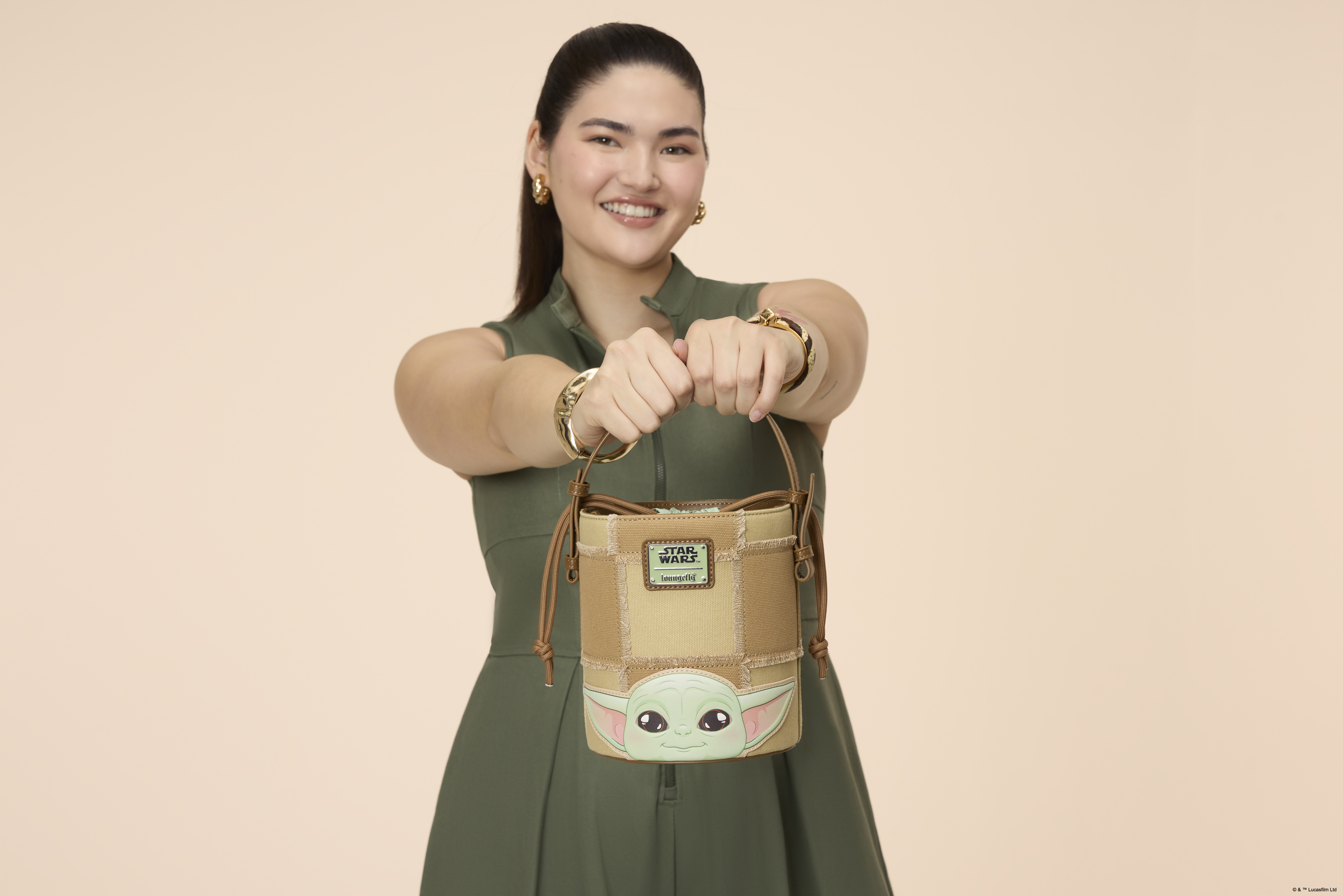 A woman holding a Loungefly bucket crossbody bag in a pink environment