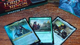 Three cards on a wooden table from the MTG Lord of the Rings Starter Set