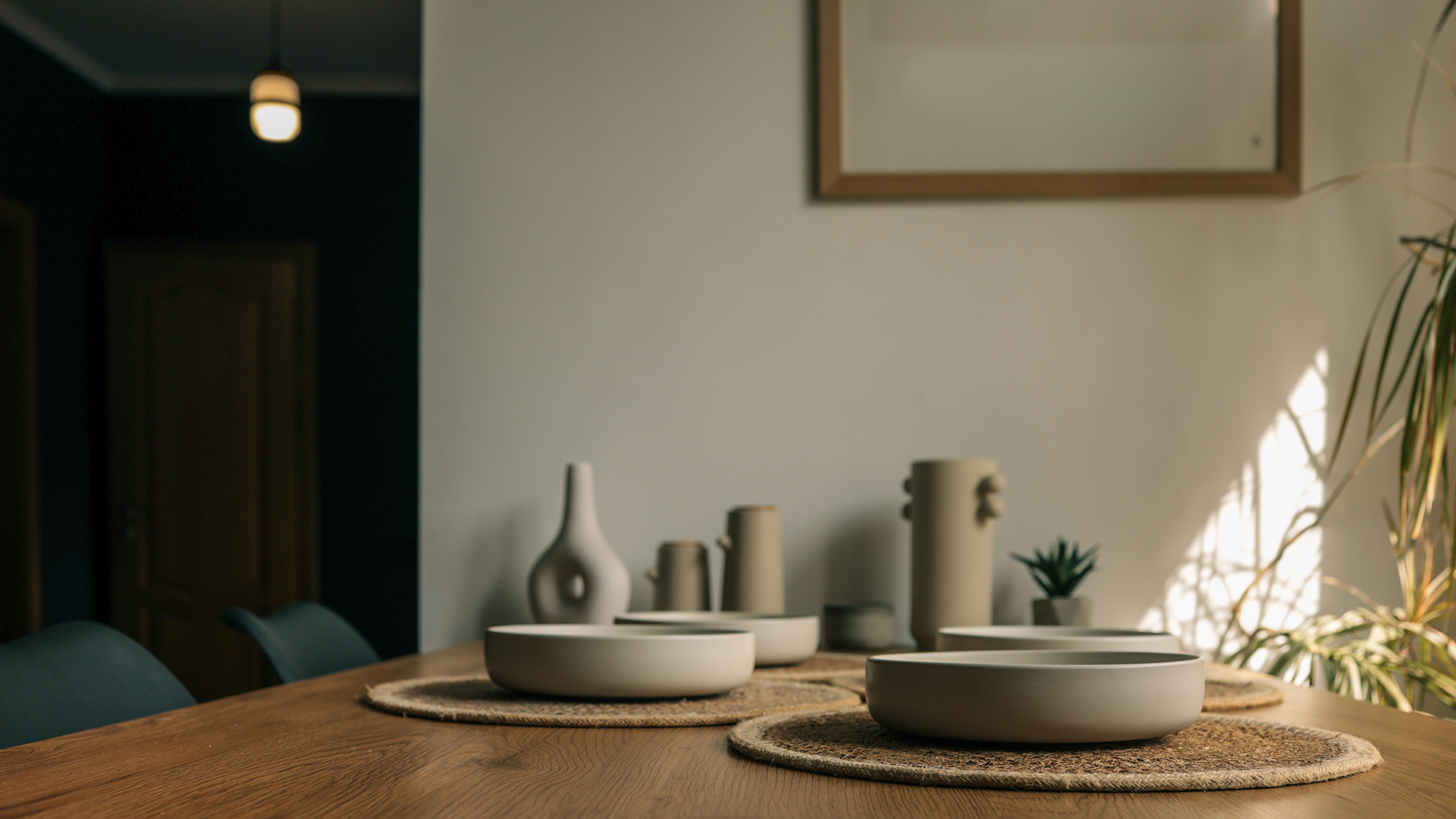 Wooden table adorned with neutral-toned ceramic bowls and decorative vases