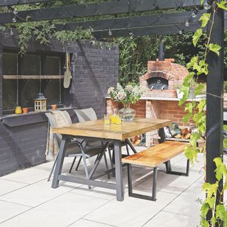 Outdoor kitchen patio with dining table and pizza oven