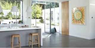 white and grey kitchen with a large kitchen island with grey tiled floors to support a guide on what you need to know before installing underfloor heating