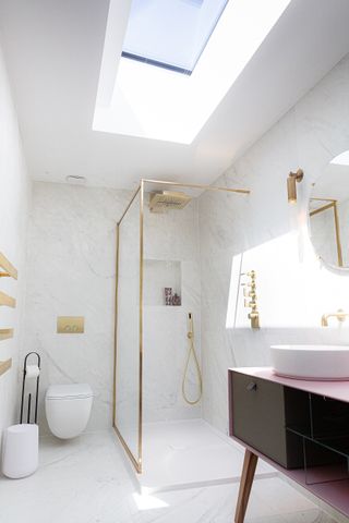 white bathroom with brass and gold details and lighting