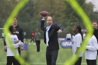 Prince William standing on a field throwing a football through a goal