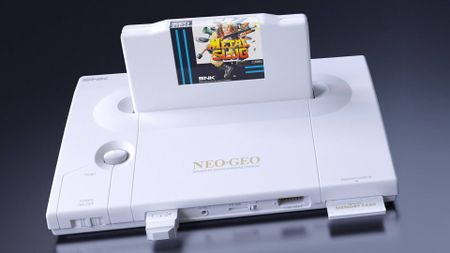 White Neo Geo AES+ console with wireless controller adapter and memory card inserted with Metal Slug cartridge on top.