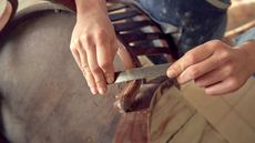 Someone sanding a small section of a wooden chair