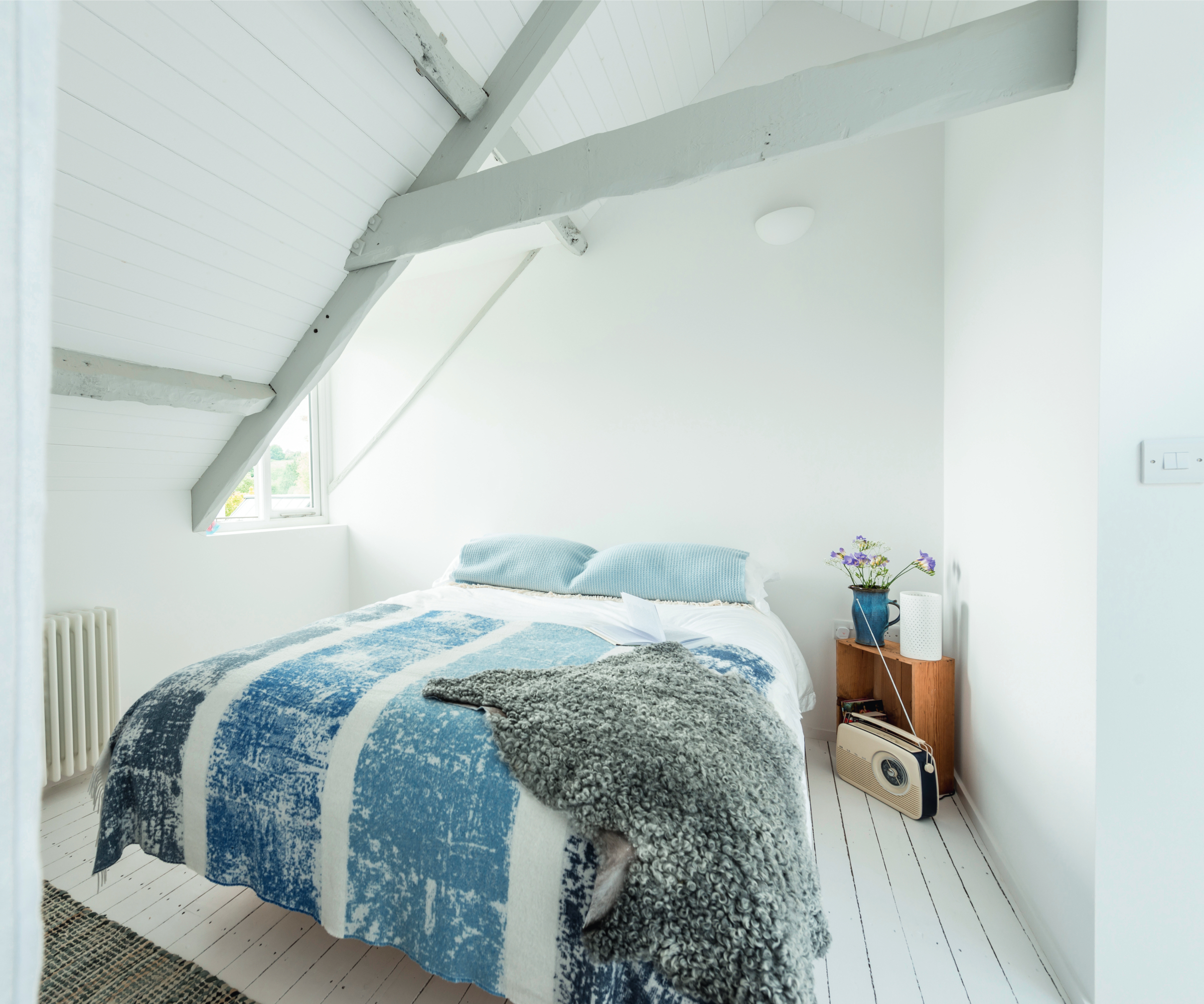 all white loft bedroom with bed and blue bedding