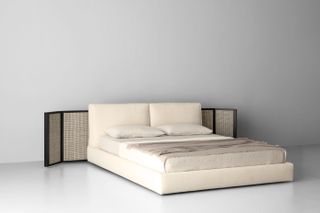 A cream coloured bed with a back panel in woven raffia with black wooden frame