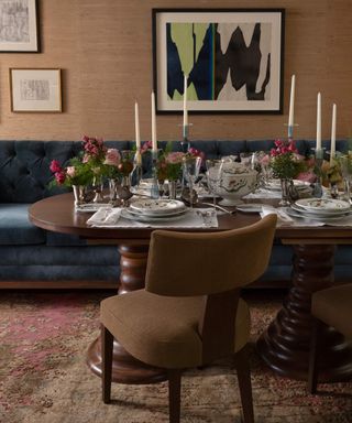 Dining table with chair in front and banquette behind dressed with flowers, candles and tableware