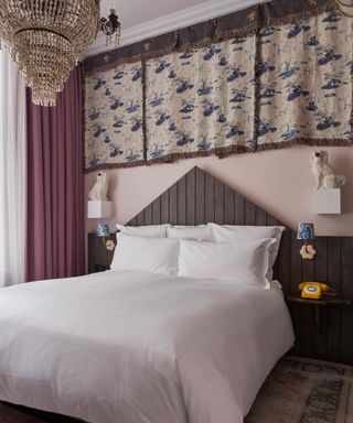 A light purple bedroom with a wooden bedframe, white sheets, and porcelain-inspired drapery above the bed