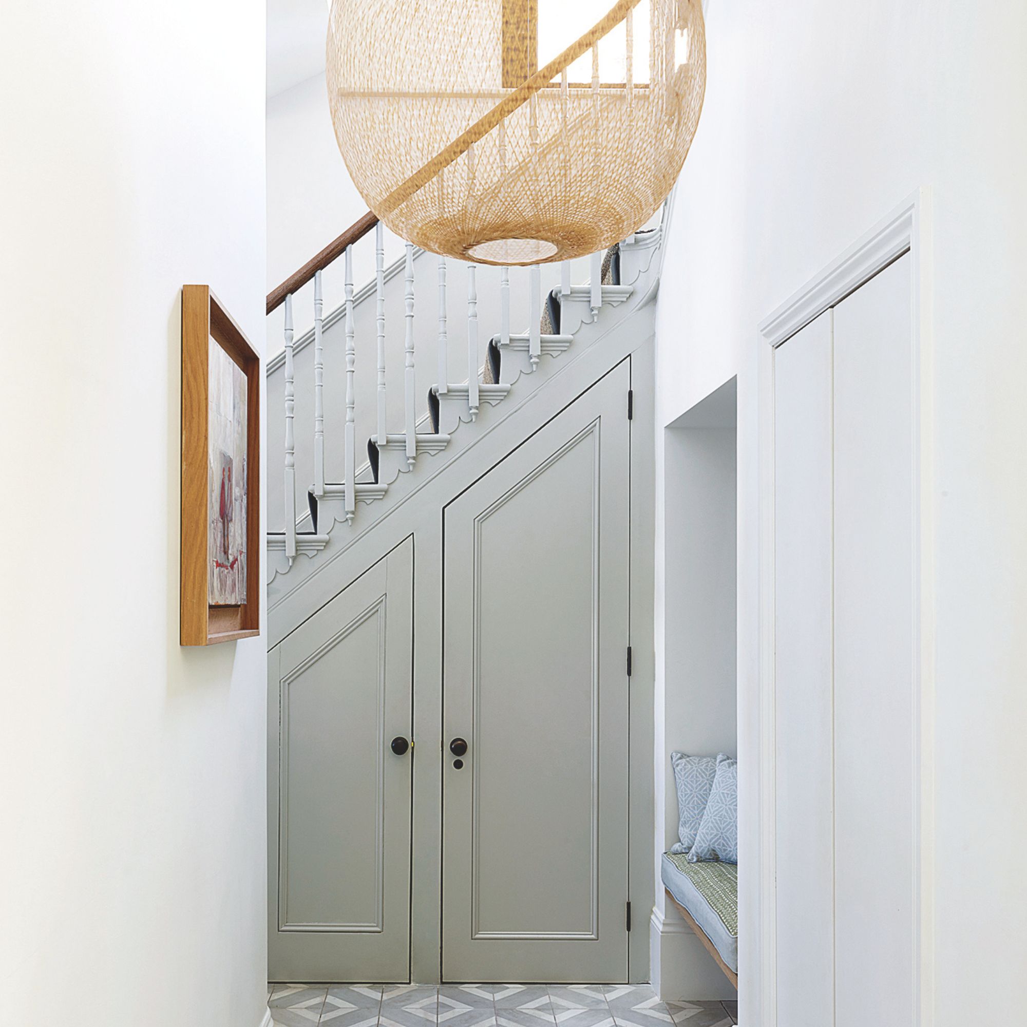 White painted hallway with stairs and an under-the-stairs cupboard underneath