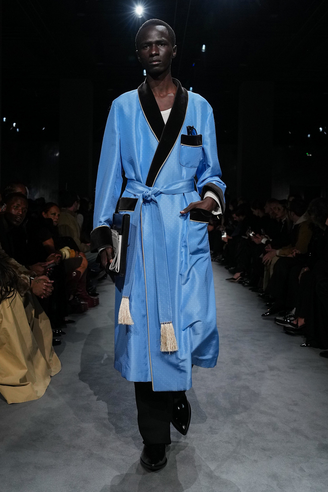 A male model wearing a blue-and-black robe walking in Haider Ackermann's first Tom Ford runway show during Paris Fashion Week.