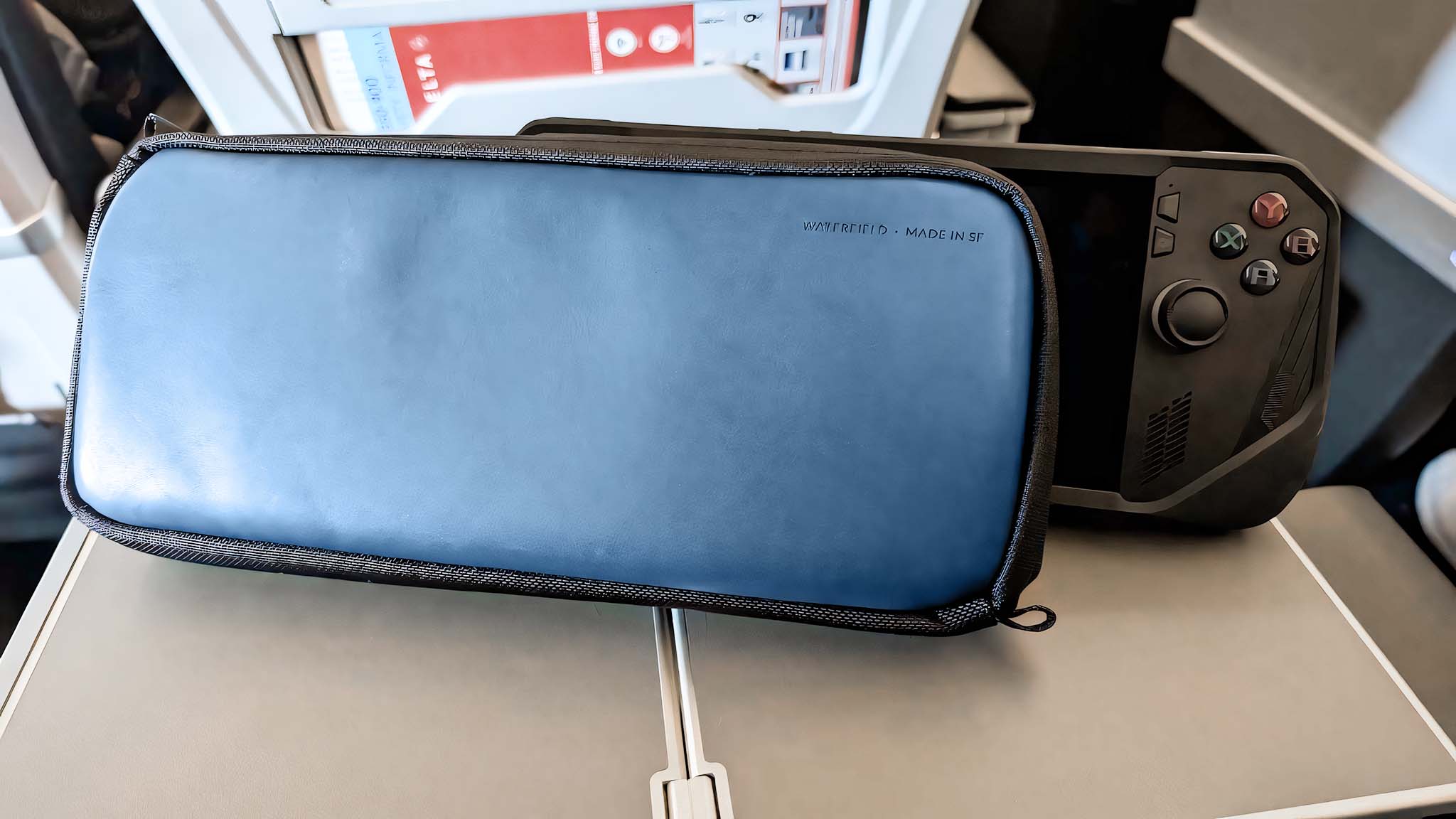The Waterfield ROG Ally X Magnetic Case in front of the Ally X on an airplane tray. 
