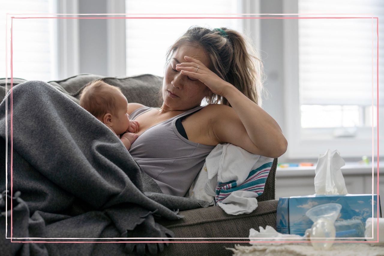 A woman with her head in her hands and a baby on her chest