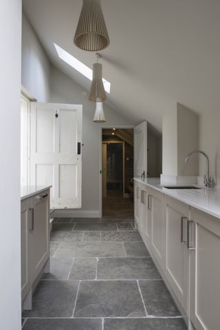 Narrow utility room ideas showing a sloped ceiling with feature lighting and grey stone flooring