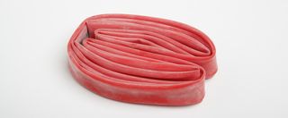 bike inner tubes can be made from latex, like the one in the image which is the colour red, folded up and on a white background.