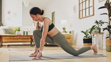 woman wearing leggings and crop top performing a hip flexor mobility stretch in a living room setting