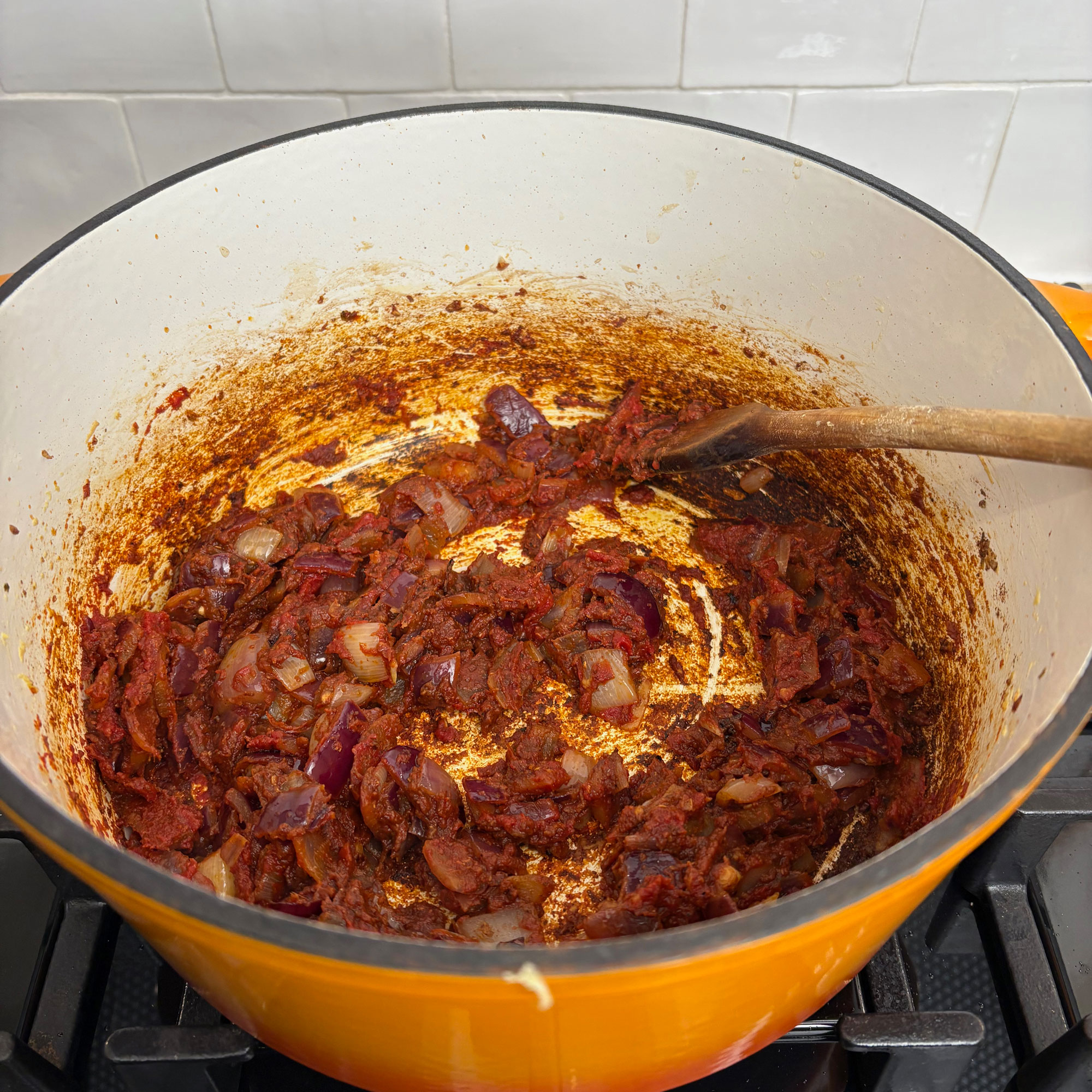 Orange cast iron pan on black hob with red mixture