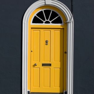 Yellow front door with white frame on dark house