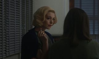 anne hathaway smokes a cigarette in 60s era clothing in the movie eileen