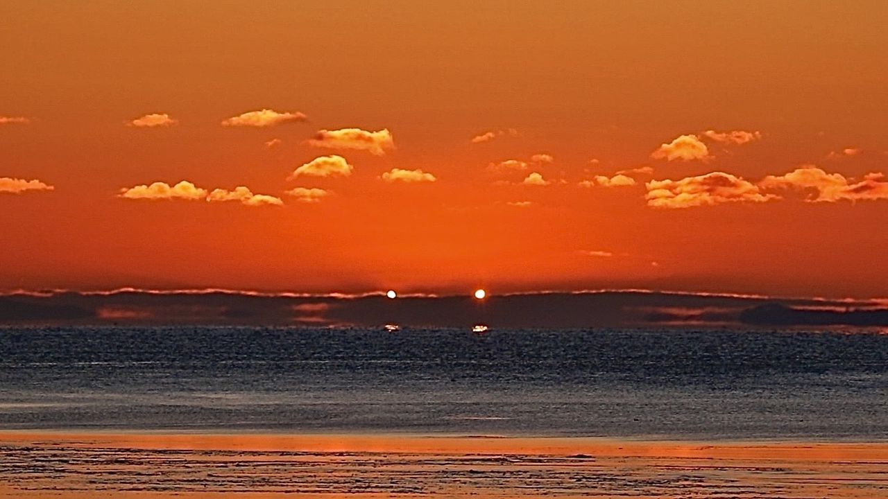 sun rising during partial solar eclipse looks like a pair of menacing horns against a red early morning sky.