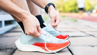 Man tying the laces on a pair of running shoes outside