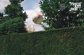Football flying over a green hedge
