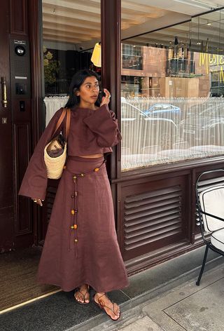 A woman wearing a matching linen set and carrying a raffia tote bag.