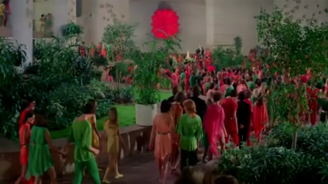 A colorful set piece with lots of people and plants in Logan's Run