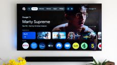 Philips OLED 809 TV on wall with Google TV running on the screen &ndash; Sonos Arc soundbar underneath