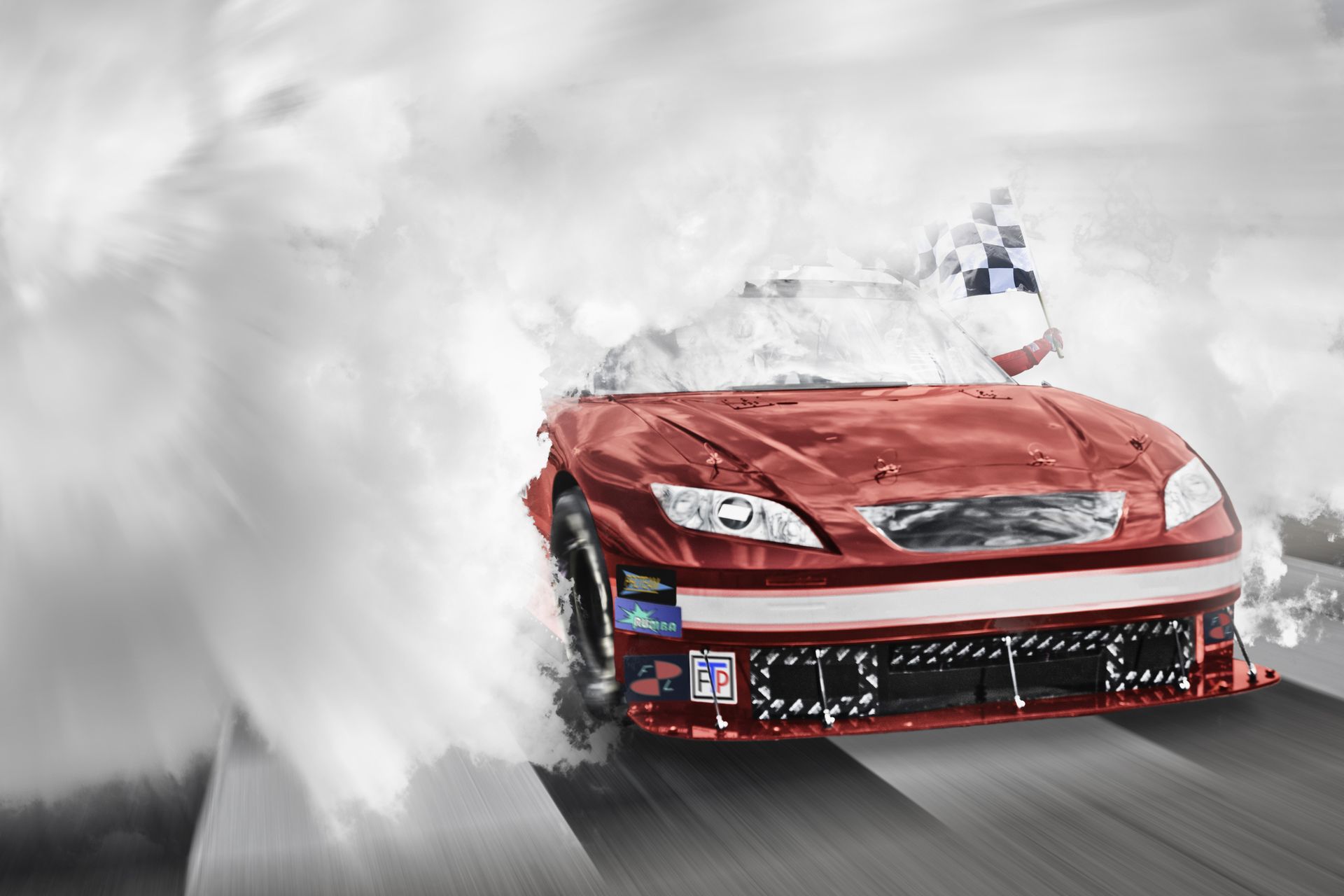 Red racing car passing the finish line coming out of smoke