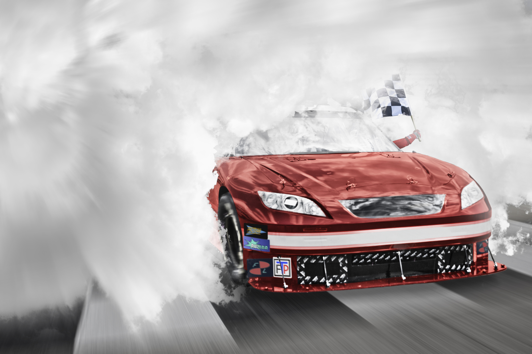 Red racing car passing the finish line coming out of smoke